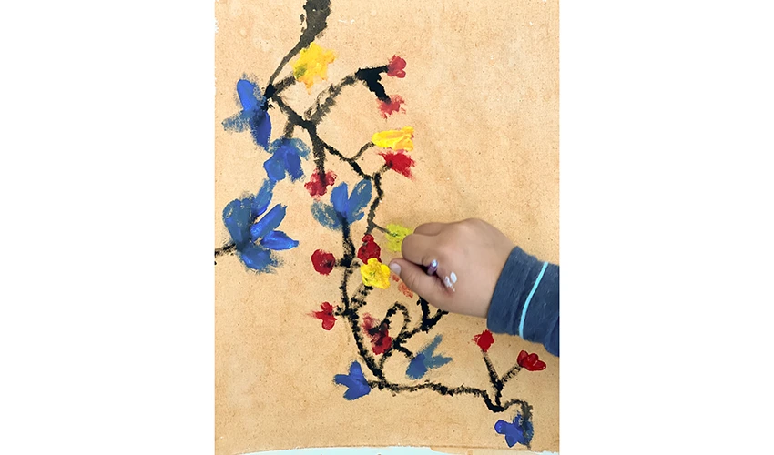 photo of a small hand painting a flower on canvas